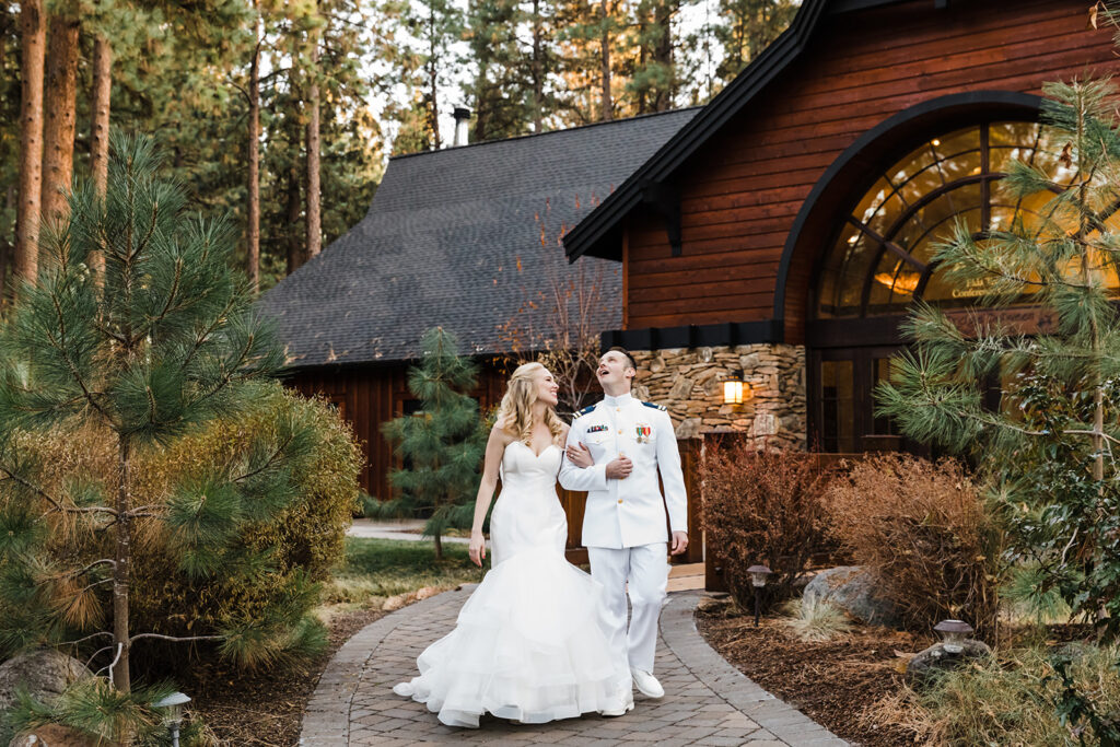 bride and groom walking hand in hand with FivePine Lodge wedding venue in the backdrop