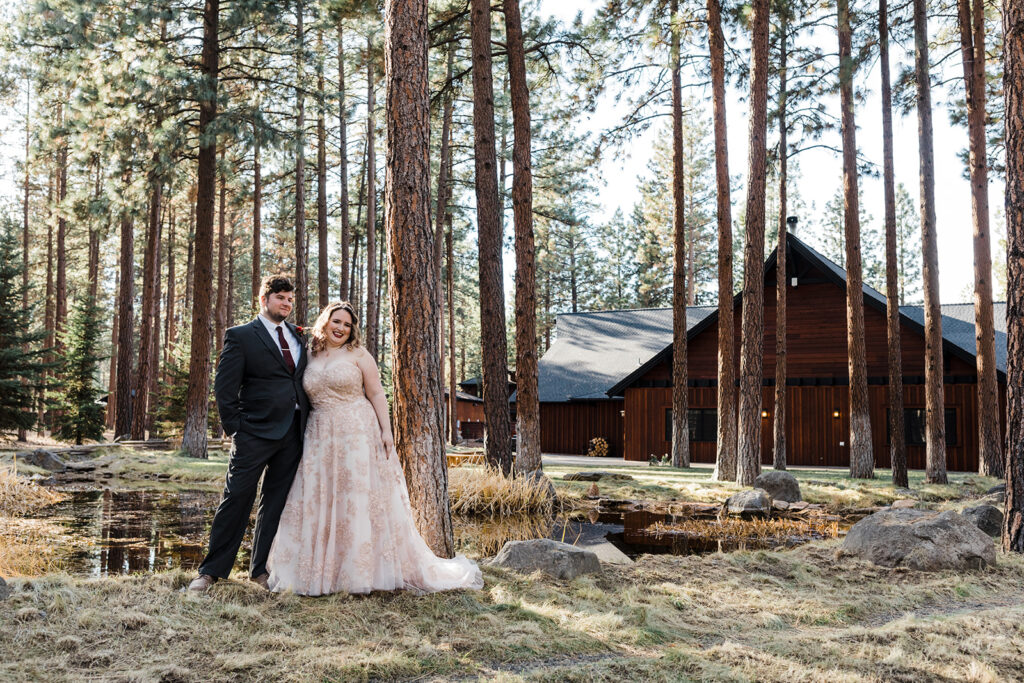 bride and groom with a forest and cozy cabins in the backdrop