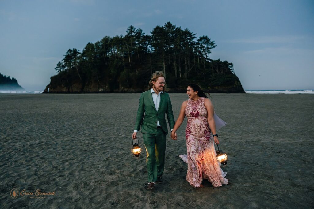 bride and groom carrying lanterns at the beach during sunrise