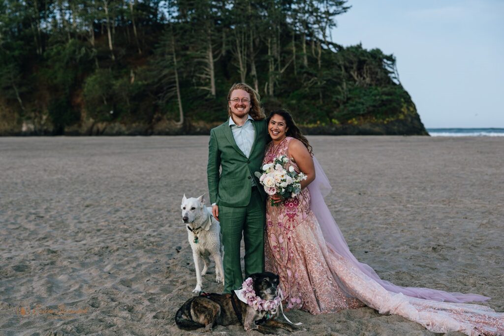 bride and groom and their two dogs at the beach in oregon coast