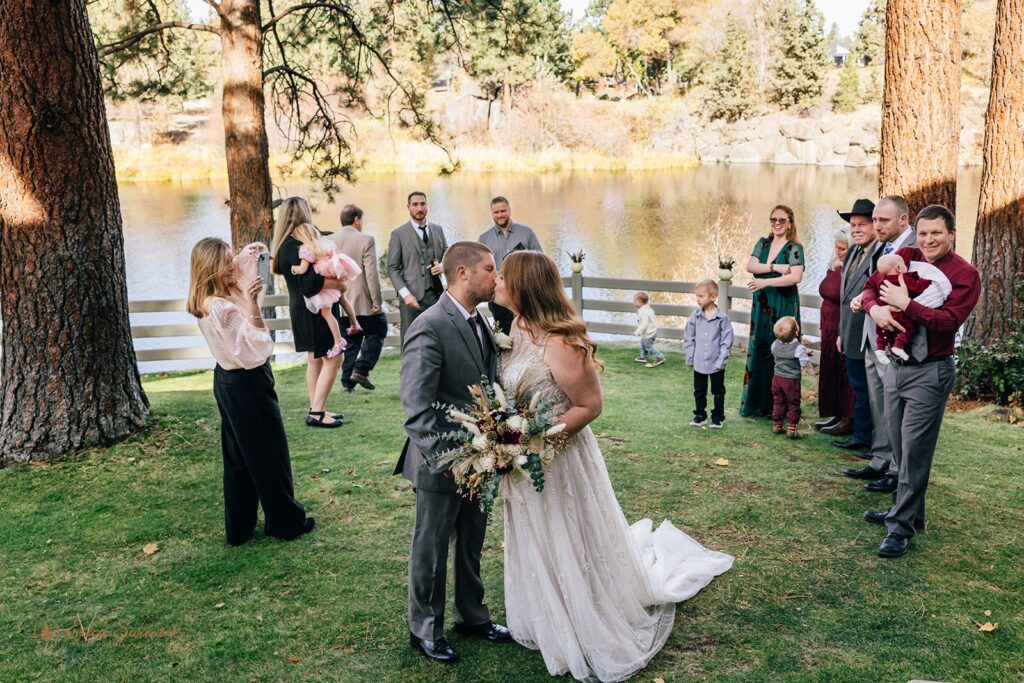 bride and groom kissing surrounded by their loved ones