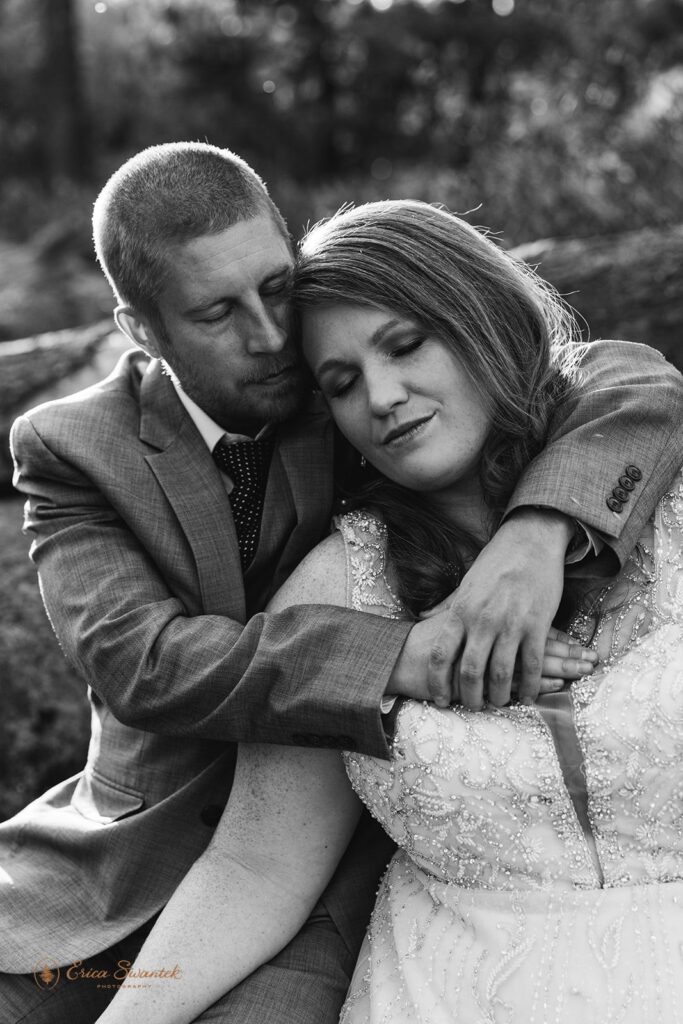 candid black and white image of bride and groom hugging