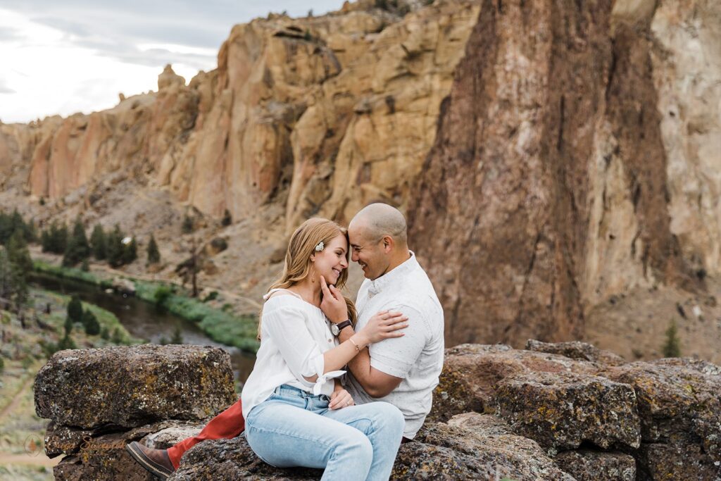 playful couple sitting on a rock during their session at smith rock state park