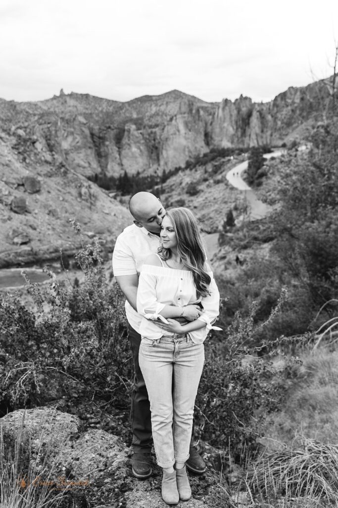 man hugging his bride from behind with smith rock backdrops