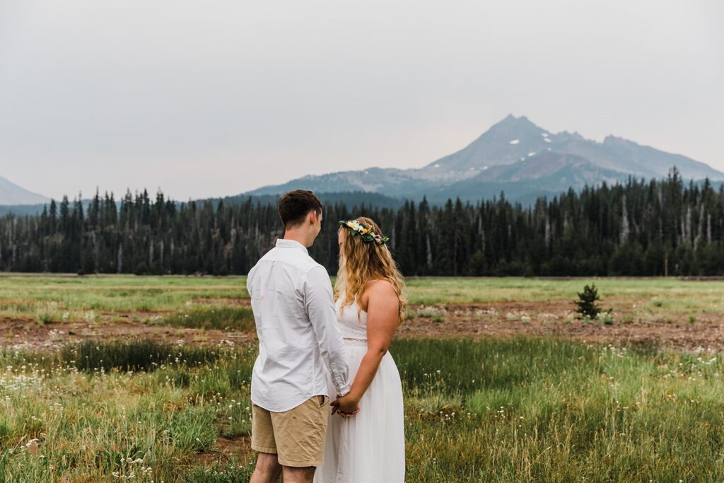 intimate elopement ceremony in a field with mountain backdrops at Sparks Lake 