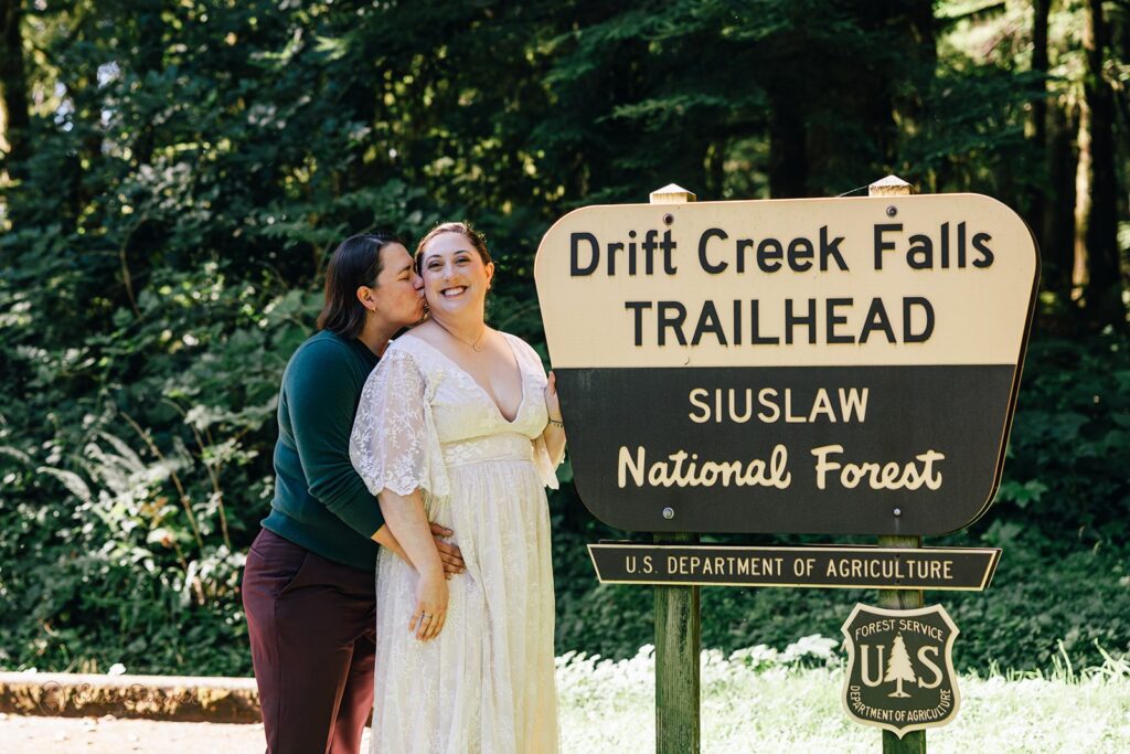 lgbtq elopement couple posing at the trailhead sign
