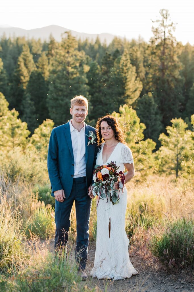 bride and groom roaming around a lush meadow in Shevlin Park with mountain and forest views in the backdrop