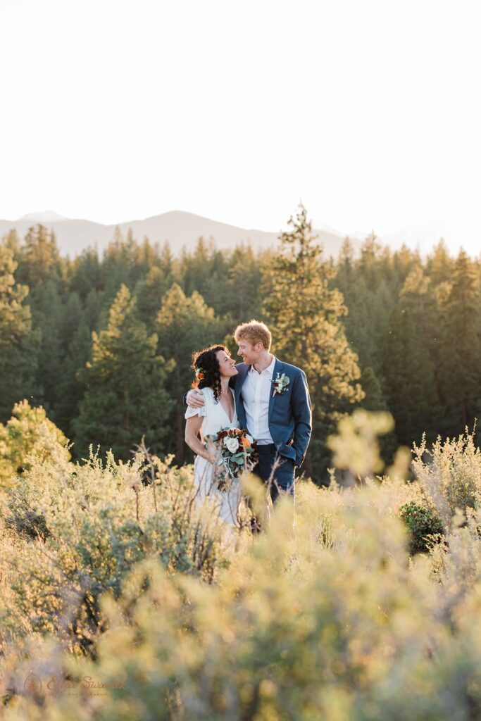 bride and groom roaming around a lush meadow in Shevlin Park with mountain and forest views in the backdrop