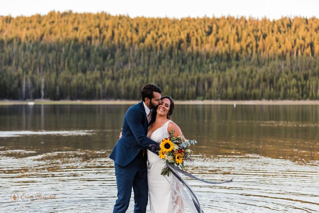 bride and groom standing in the water with mountain and forest views in the backdrop