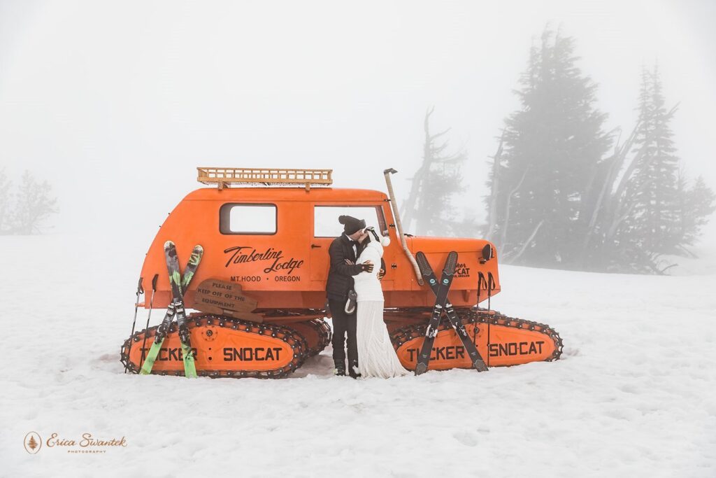 elopement couple posing at a large orange sno cat during their winter elopement in mt. hood