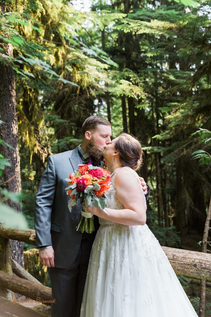 bride and groom kissing surrounded by lush forests