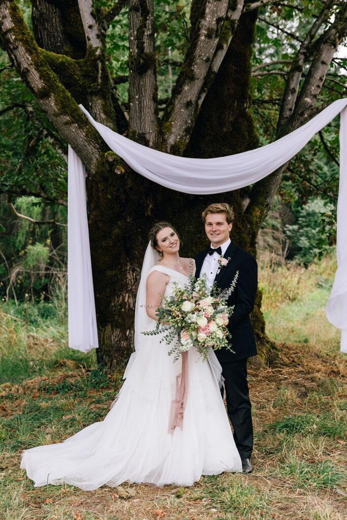 bride and groom posing under their ceremony tree