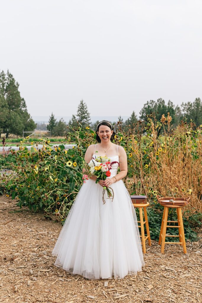 bride posing next to a colorful flower field at rainshadow organics farm