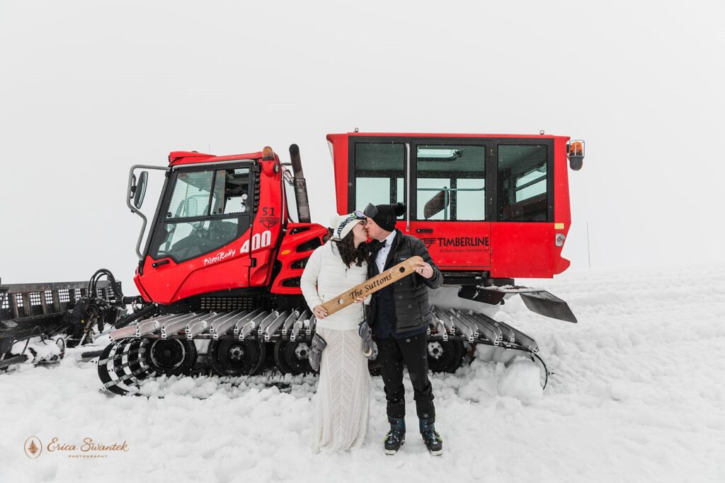 bride and groom posing next to a snowmobile during their winter elopement at silcox hut