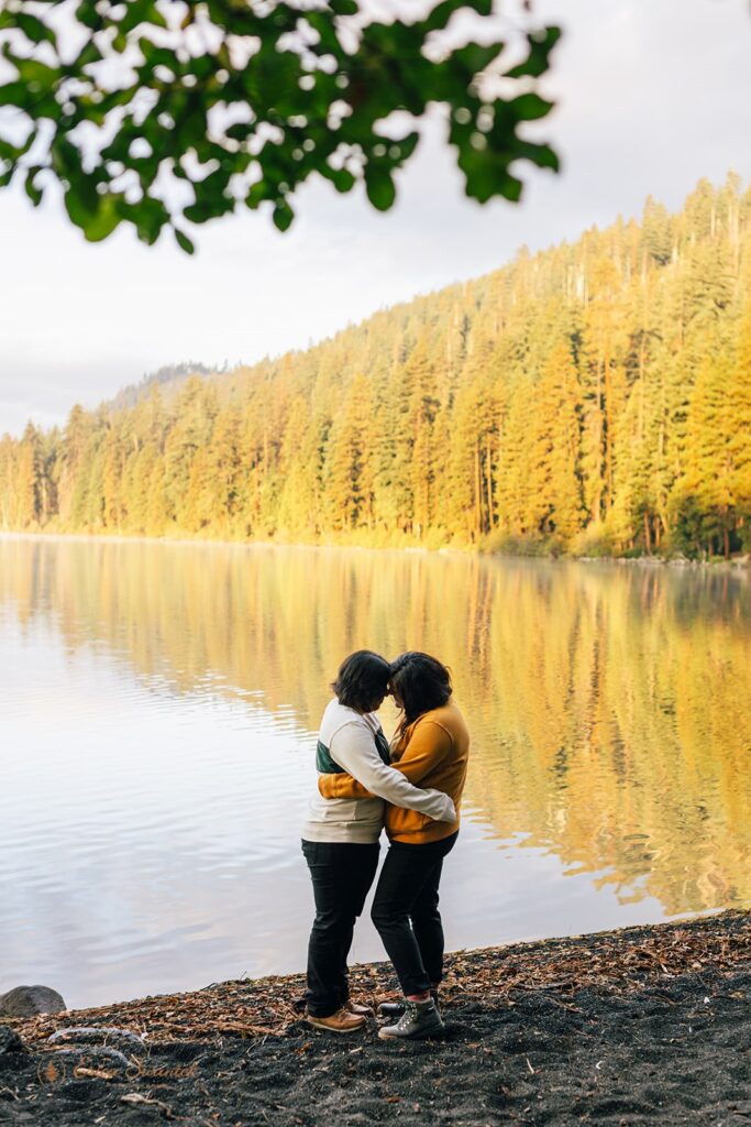 sweet couple hugging by suttle lake with golden trees in the backdrop