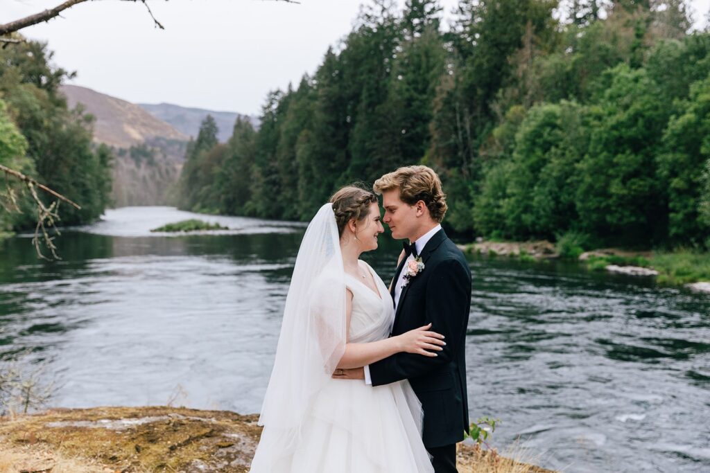 bride and groom surrounded by lush forest and water views