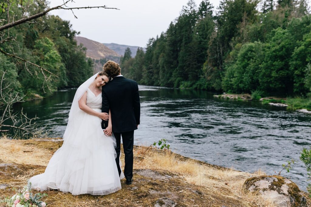 bride and groom surrounded by lush forest and water views