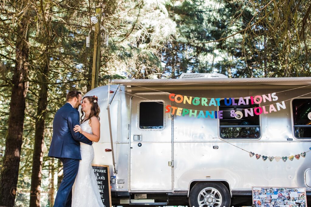 intimate forest wedding at hornings hideout, bride and groom posing next to a decorated RV