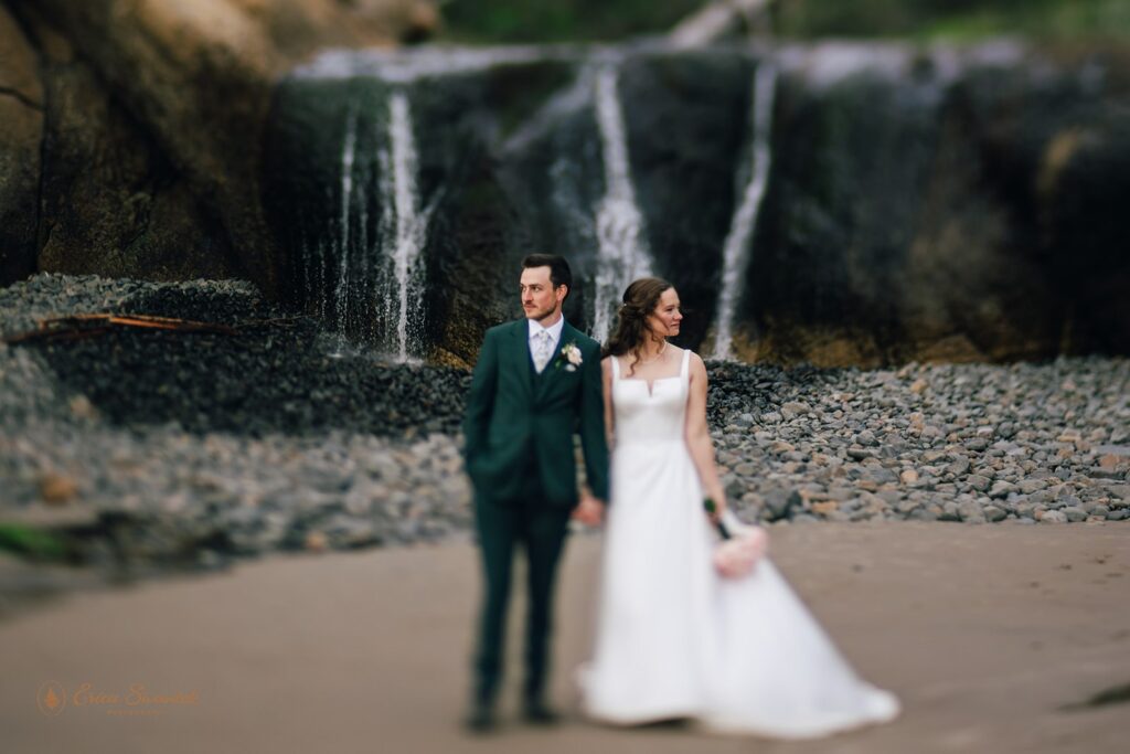 bride and groom in front of a small waterfall at oregon coast