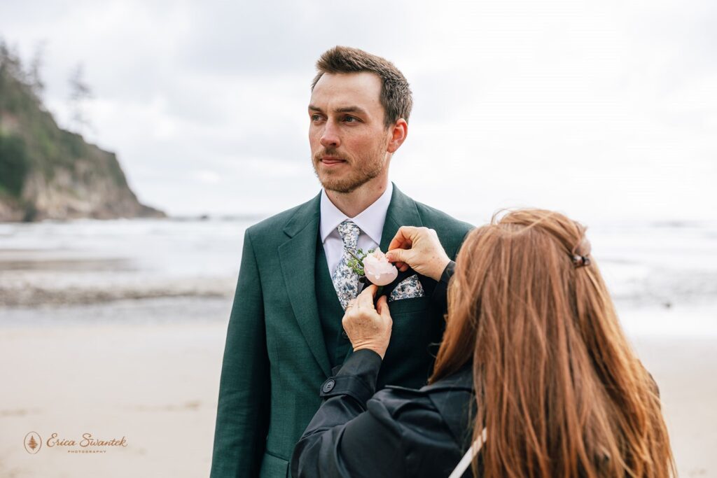mom pinning a boutonniere on the groom