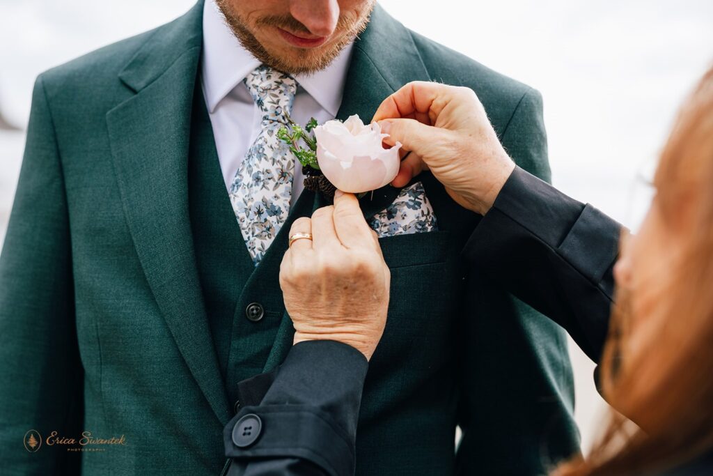 mom pinning a boutonniere on the groom