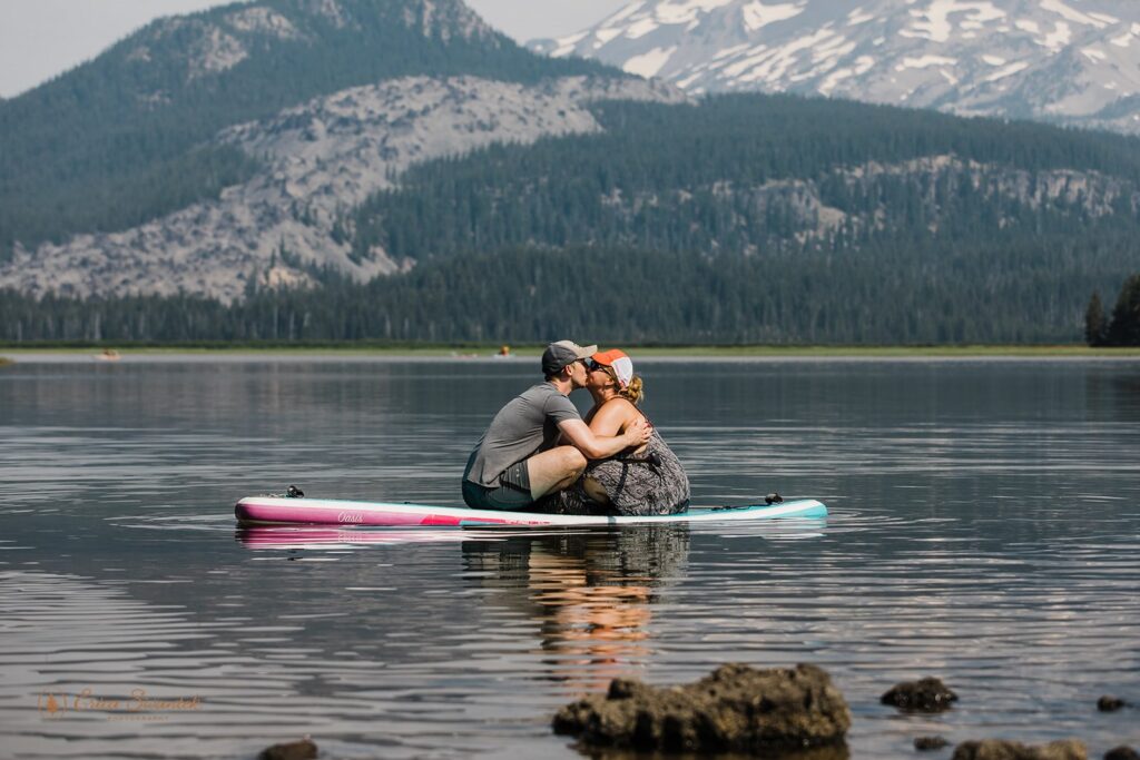 bride and groom kissing on the paddle board