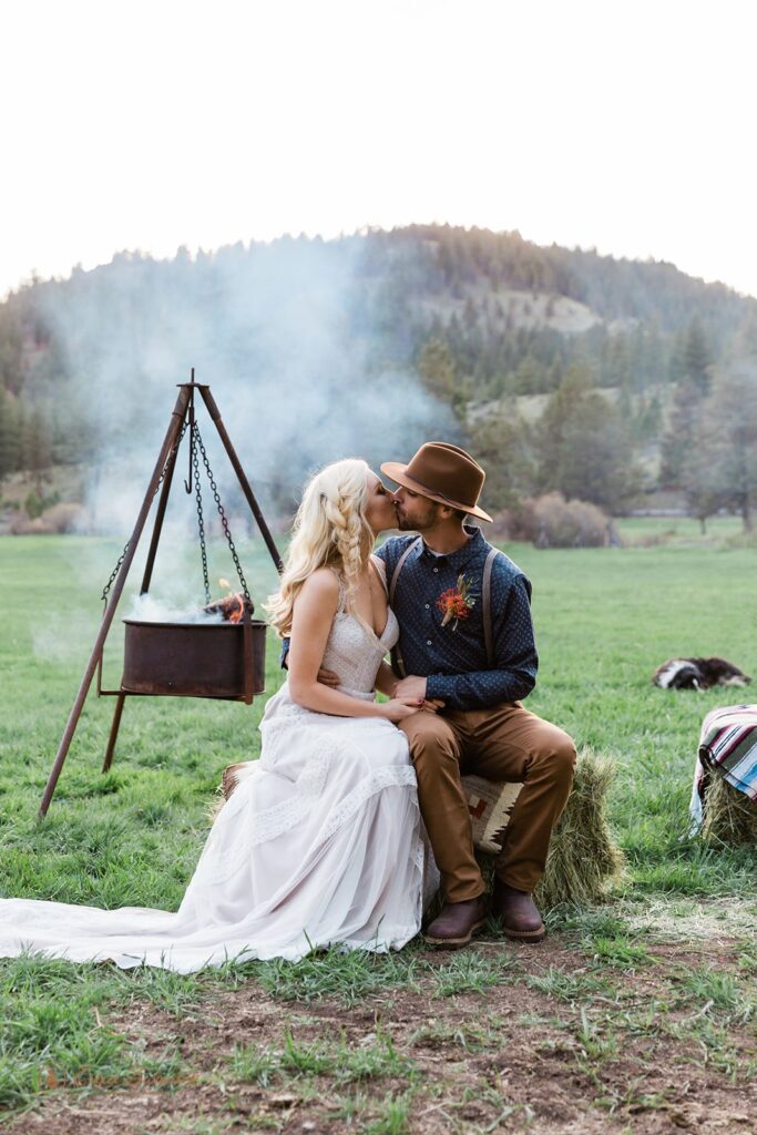 bride and groom kissing next to a campfire