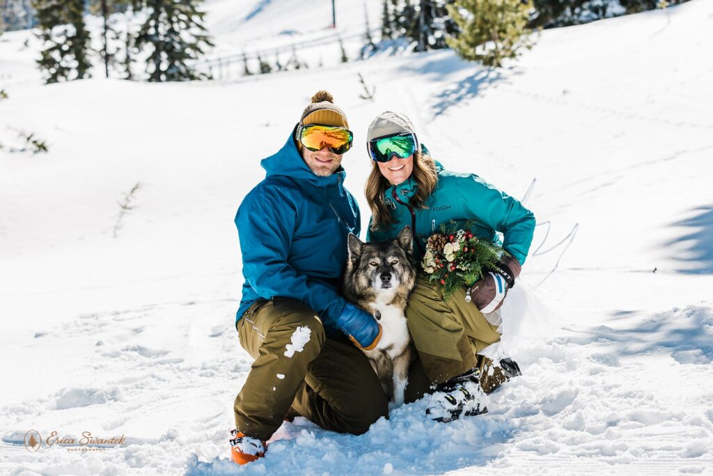 newlyweds and their dog surrounded by snow