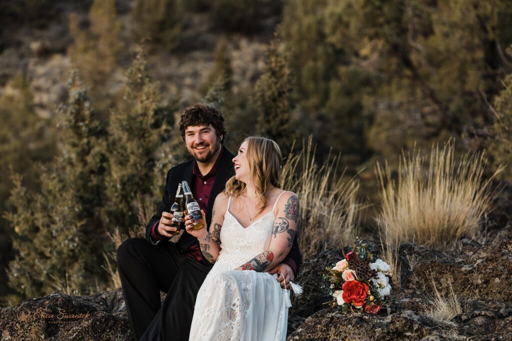 bride and groom toasting beers as they celebrate their elopement