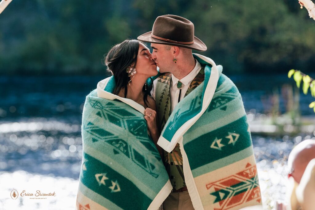 bride and groom wrapped up in a colorful pendelton blanket
