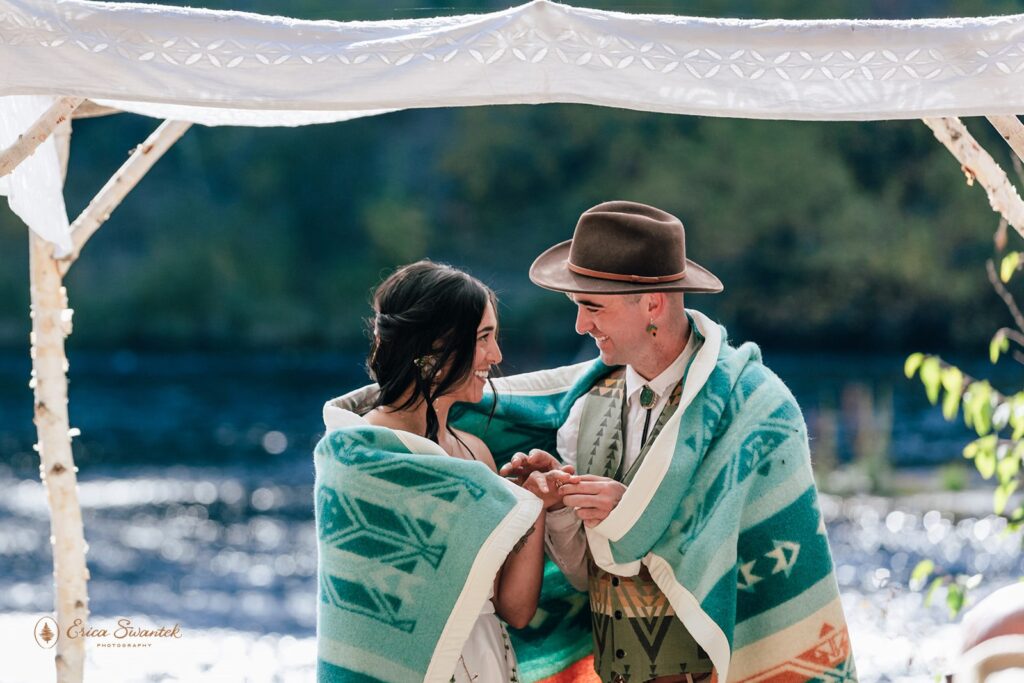 bride and groom wrapped up in a colorful pendelton blanket