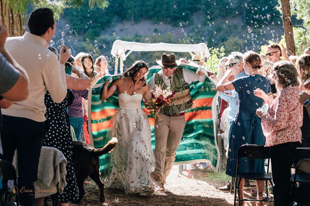 joyful newlywed ceremony exit while guests blow bubbles