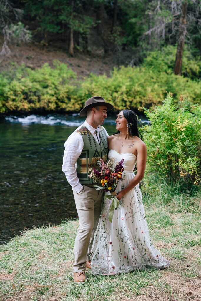 bride and groom together next to the Metolius River during their campground wedding