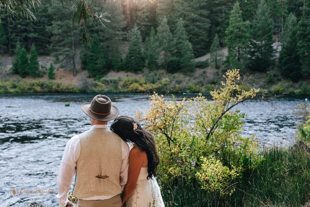 bride and groom snuggling and gazing onto the metolius river