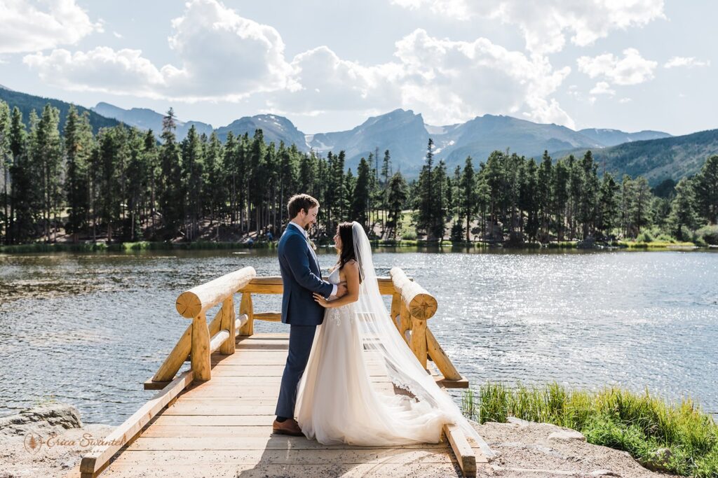 bride and groom on a small wooden deck on sprague lake in rmnp