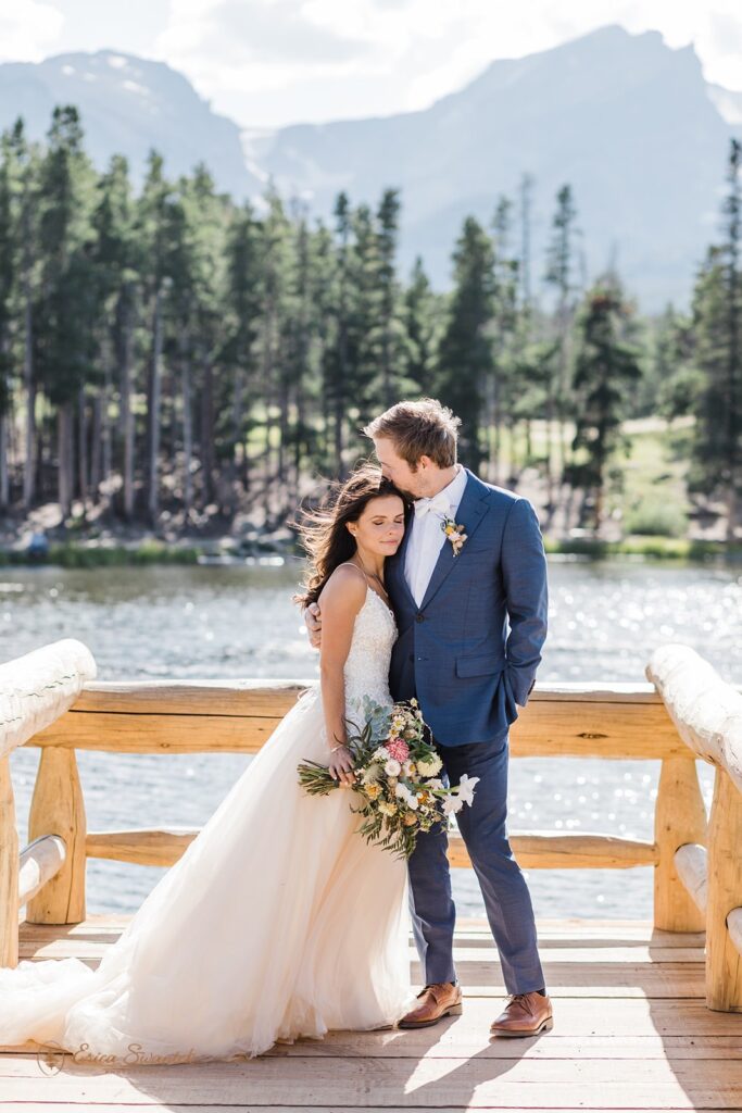groom kissing bride on top of her head during their rocky mountain national park elopement in sprague lake