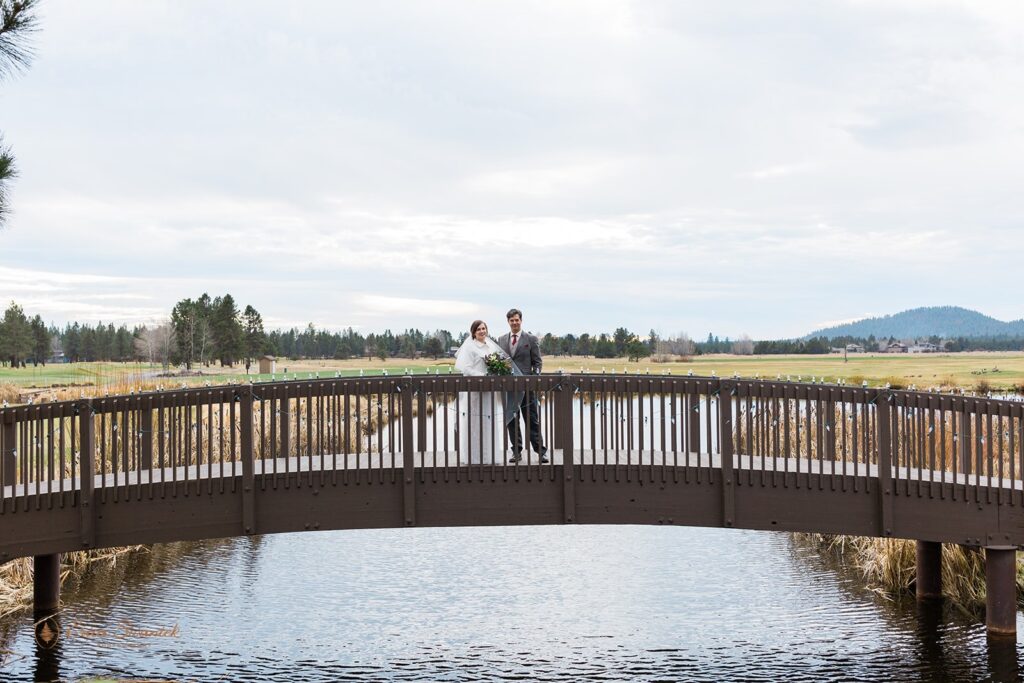 wedding couple walking across a bridge during their sunriver resort wedding day
