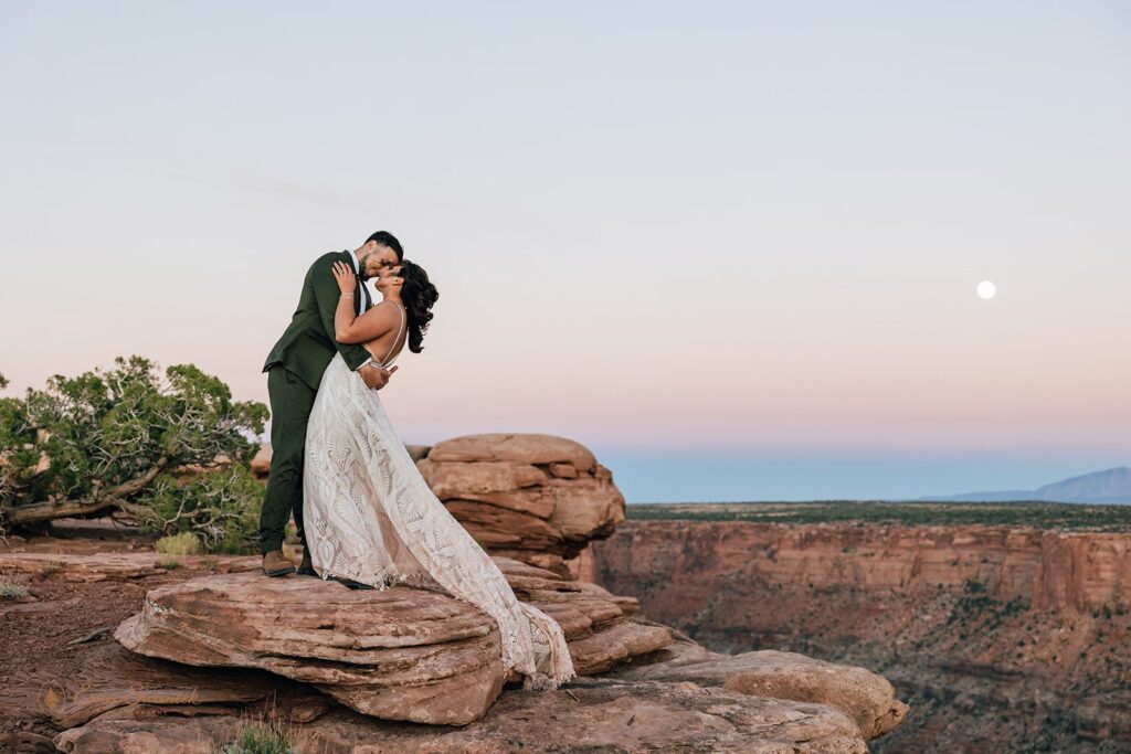 bride and groom kissing surrounded by red rock landscapes in moab