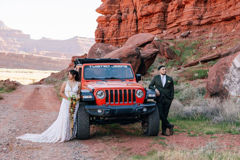 bride and groom standing next to an orange jeep during their adventure elopement in moab