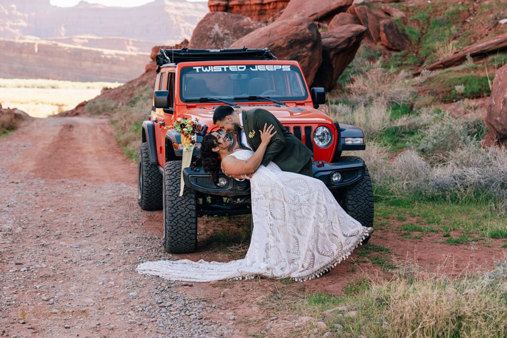 bride and groom kissing in front of an orange jeep during their adventure elopement in moab