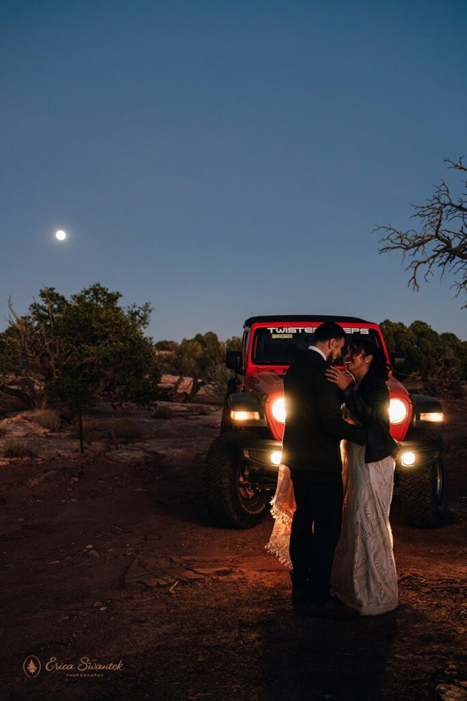bride and groom kissing in front of the jeep with full moon in the background