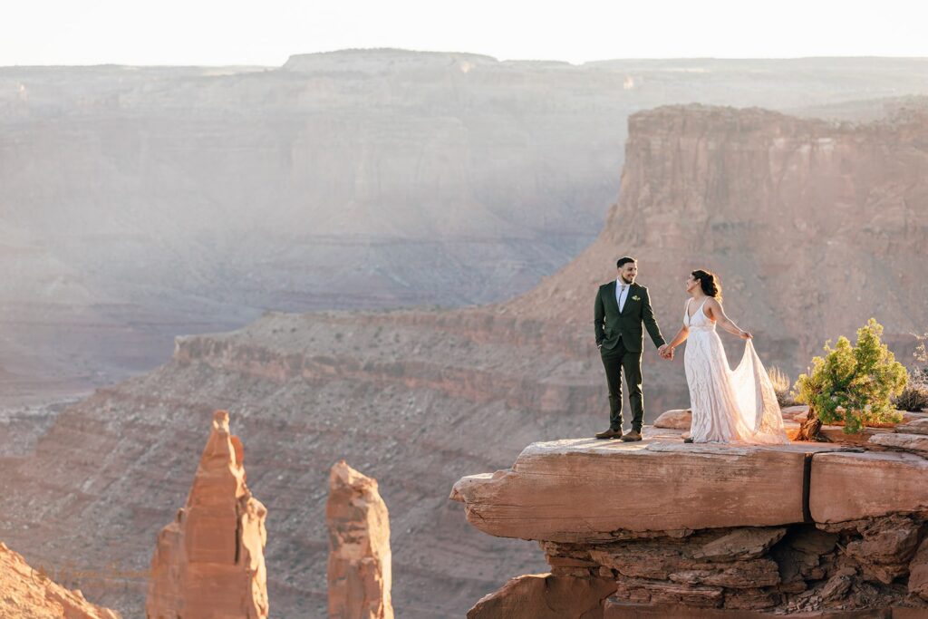 bride and groom holding hands surrounded by red rock landscapes in moab