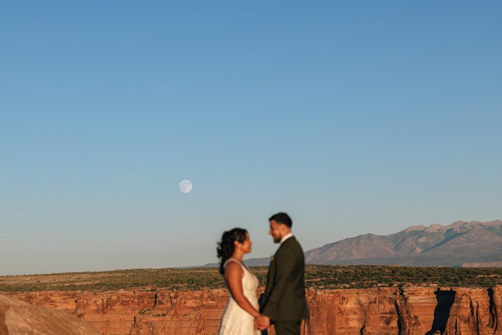 bride and groom holding hands surrounded by red rock landscapes in moab