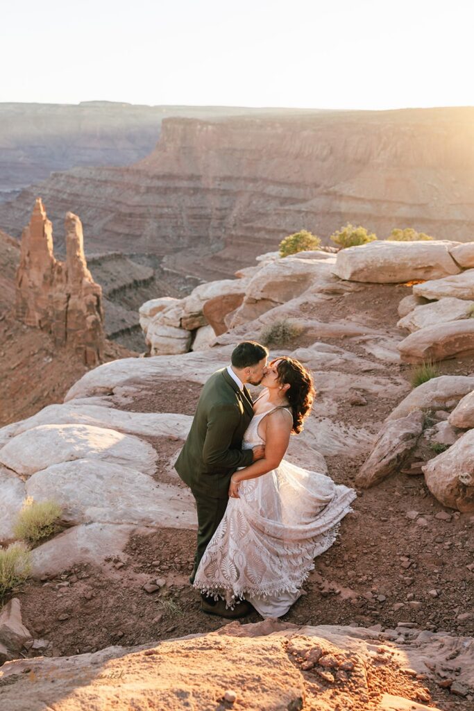 bride and groom kissing surrounded by red rock landscapes at marlboro point in moab
