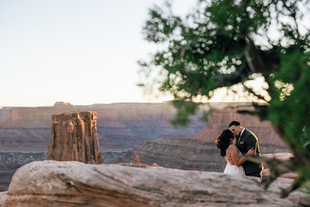 bride and groom kissing surrounded by red rock landscapes at marlboro point in moab