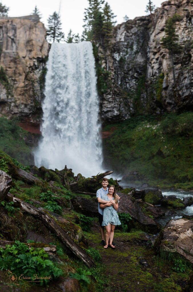 sweet couple getting soaked in front of a waterfall during their session in pnw