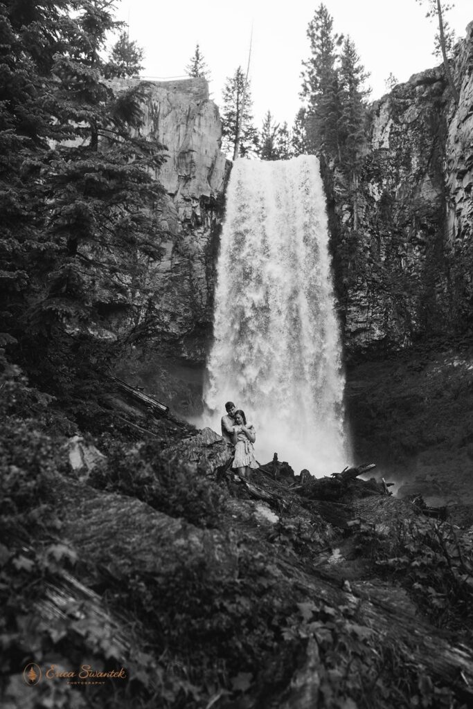 sweet couple getting soaked in front of a waterfall during their session in pnw
