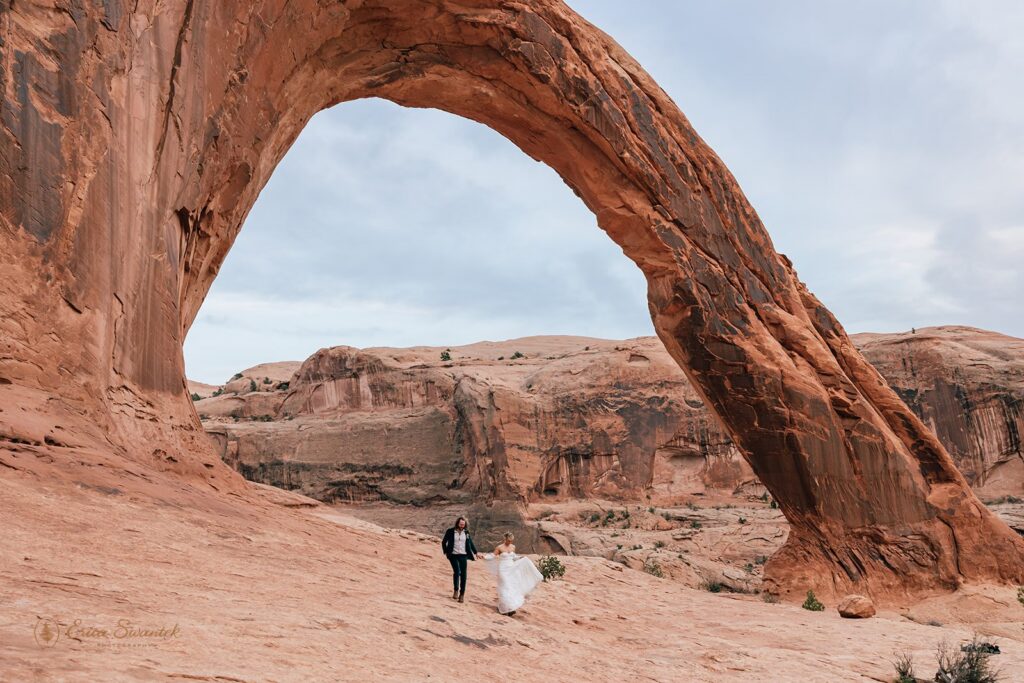 elopement couple hiking the corona arch for their moab adventure elopement