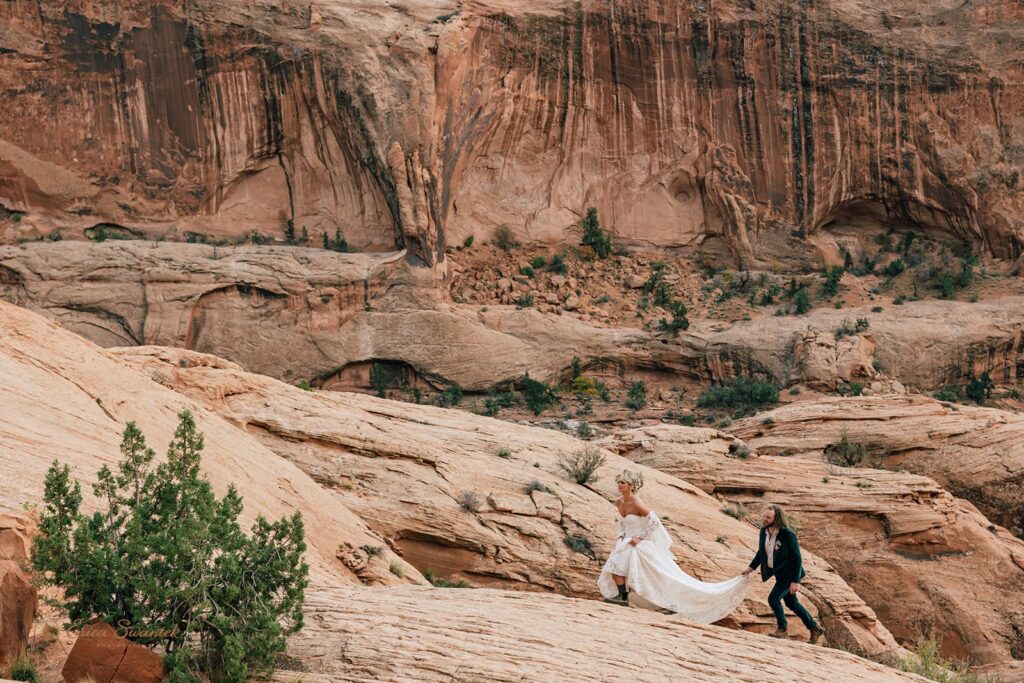 adventurous elopement couple hiking the red rock cliffs in moab during their skydiving wedding day