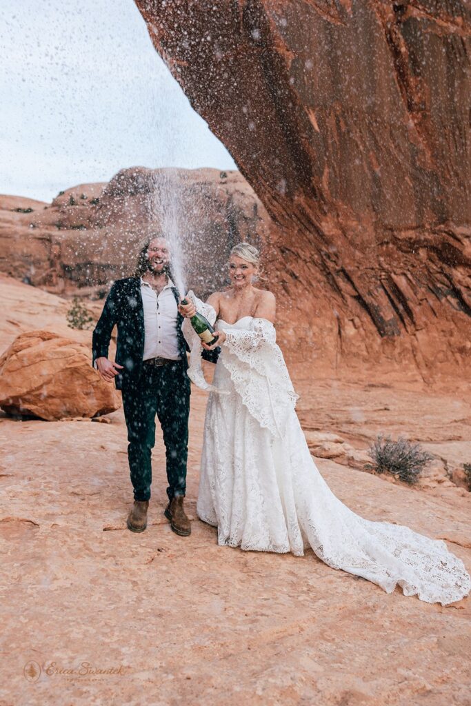 bride and groom popping champagne during their moab desert elopement